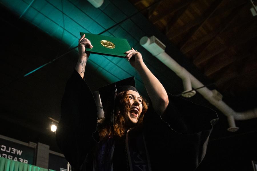 周六，<a href='http://aybvpg.gpsautotracker.net'>网上赌博网站十大排行</a>的一名毕业生在毕业典礼上展示她的毕业证书.