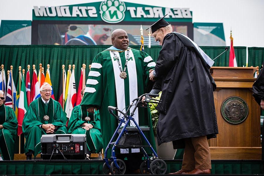 Dr. 克拉伦斯•格林, who served as Northwest's interim president during the 2022-23 academic year, congratulated 戈登 Hill as he crossed the commencement stage at Bearcat Stadium. 